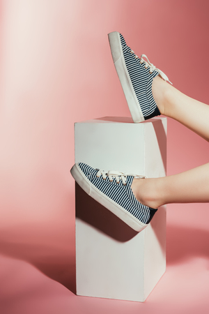 cropped shot of woman legs in stylish sneakers on pink backgroundの写真素材