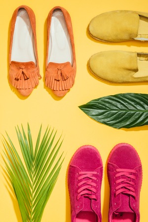 top view of tropical leaves and stylish female shoes on yellow backgroundの写真素材