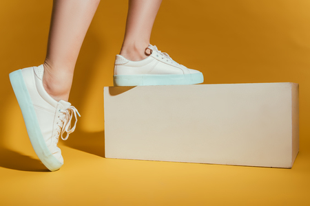 cropped image of woman feet in stylish sneakers on yellow backgroundの写真素材