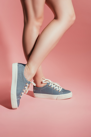 cropped image of woman legs in stylish sneakers on pink backgroundの写真素材