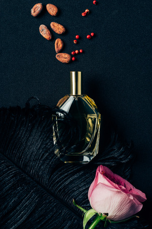 top view of bottle of perfume with rose bud and spices on blackの写真素材