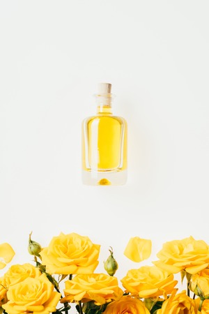 top view of bottle of perfume and yellow roses on whiteの写真素材