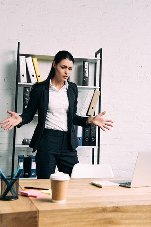 portrait of overworked businesswoman standing at workplace with laptop in officeの写真素材