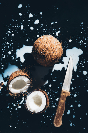 top view of coconuts, knife and coconut milk on blackの写真素材