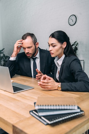 overworked business people working on laptop together at workplace in officeの写真素材