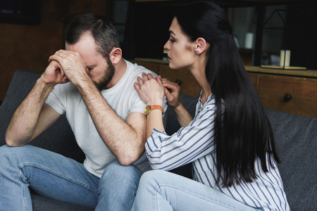 young wife asking forgiveness from husband after quarrel at home