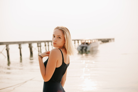 portrait of attractive girl in dress looking at camera on beachの写真素材