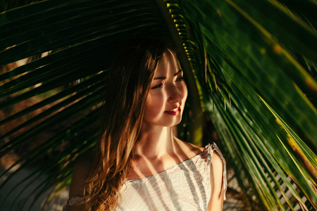 portrait of attractive girl under big green palm tree leafの写真素材
