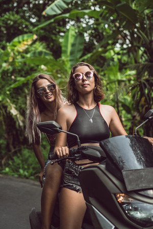 beautiful young women riding motorcycle and smiling at camera in junglesの写真素材