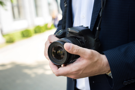 partial view of photojournalist in formal wear holding photo cameraの写真素材