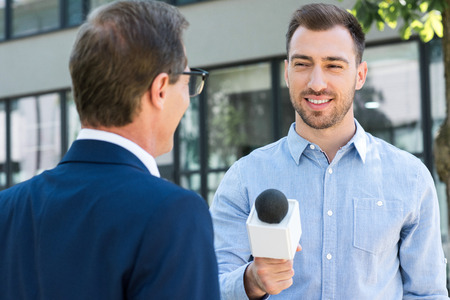 professional news reporter interviewing successful businessman with microphoneの写真素材