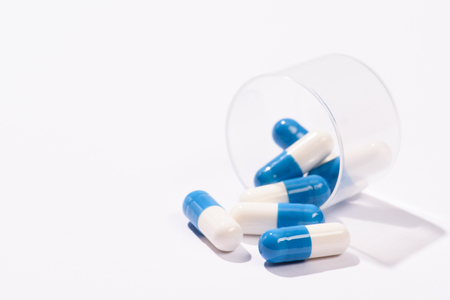 close-up shot of pills spilled from plastic can on whiteの写真素材