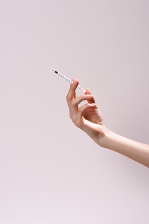 cropped shot of woman holding syringe isolated on greyの写真素材