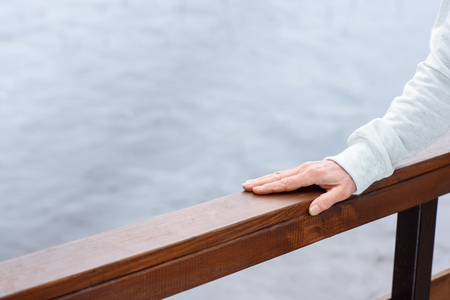 partial view of female hand on wooden railingsの写真素材