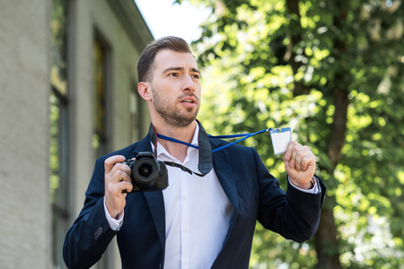 photojournalist in formal wear with digital photo camera and press passの写真素材