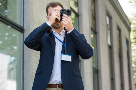 photojournalist in formal wear with press pass taking photoの写真素材
