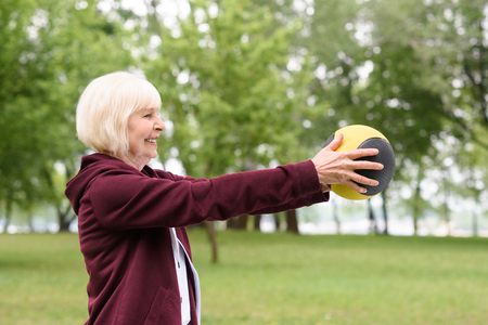 elderly woman exercising with medicine ball in parkの写真素材