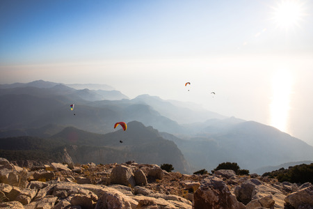 spectacular view of paragliders in sky over rocky mountains, babadag, turkey