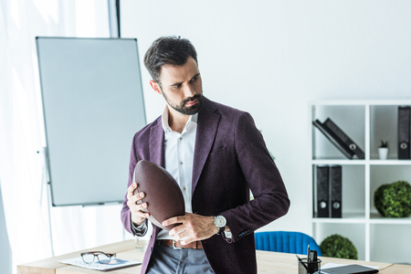 handsome young businessman with american football ball at officeの写真素材
