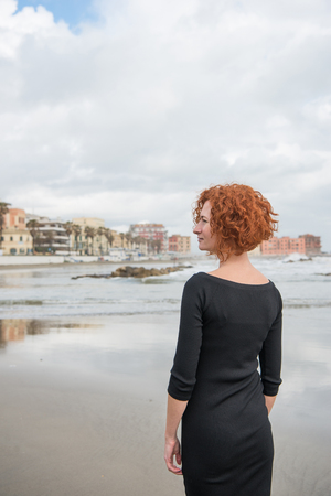 rear view of beautiful young woman on seashore on cloudy day, Anzio, Italyの写真素材