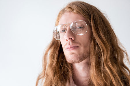 portrait of handsome man with curly ginger hair and glasses looking at camera isolated on whiteの写真素材