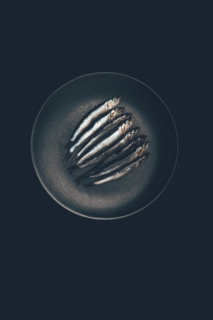 Top view of pile of fish in frying pan isolated on black