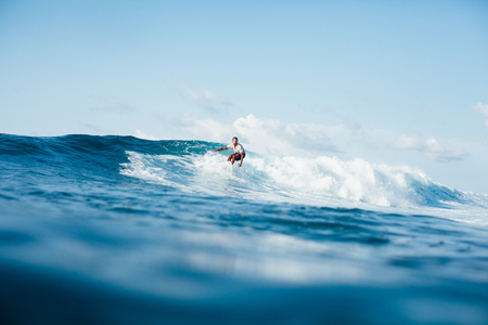 handsome athletic man surfing on ocean waveの写真素材