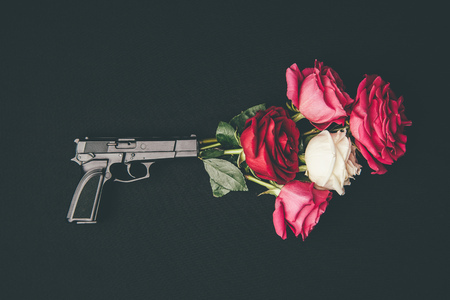 Gun shooting with bouquet of rose flowers isolated on blackの写真素材