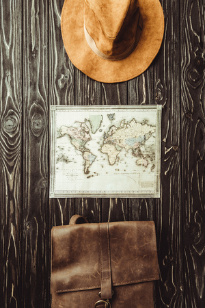 top view of arranged hat, map and bag on dark wooden surfaceの写真素材