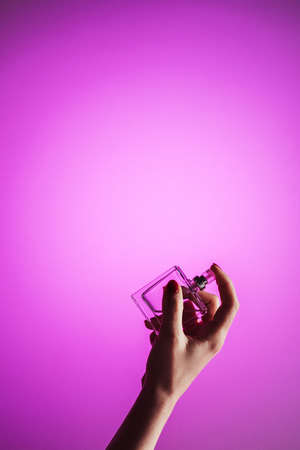 cropped view of female hand with perfume bottle, isolated on pinkの写真素材