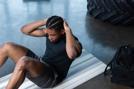 high angle view of muscular african american man doing abs in gymの写真素材
