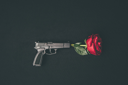 Red rose shooting from gun isolated on black