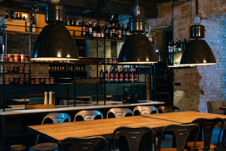 wooden tables, lamps and bar counter in modern restaurant
