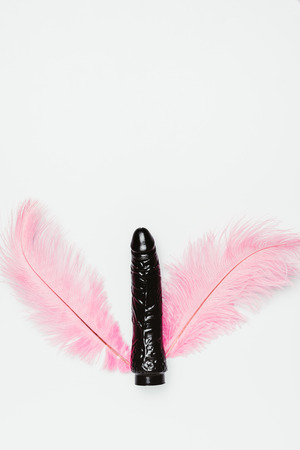 Black vibrator toy with pink feathers isolated on whiteの写真素材