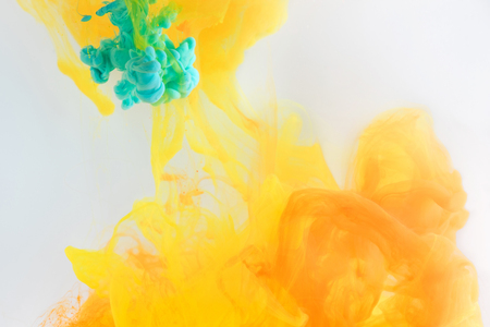 abstract texture with turquoise and orange paint splashes in waterの写真素材