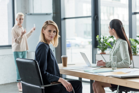 beautiful blonde businesswoman looking at camera during meeting in officeの写真素材