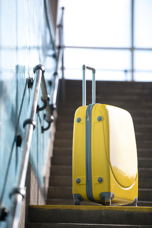 closeup shot of yellow wheeled bag on stairs at subwayの写真素材