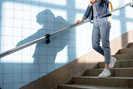 cropped shot of female traveler with backpack going downstairs at subway