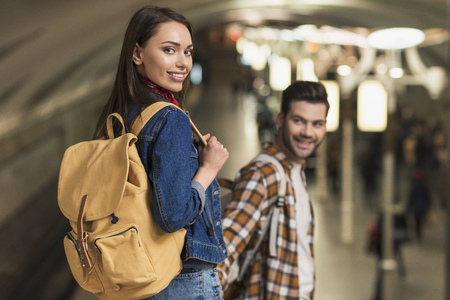 smiling female traveler with backpack and boyfriend at subway station