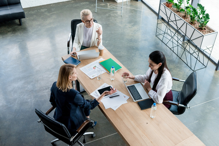 high angle view of three professional businesswomen discussing project at workplaceの写真素材