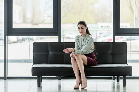 attractive businesswoman sitting on sofa in officeの写真素材