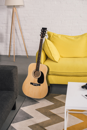 acoustic guitar near cozy yellow couch in modern interiorの写真素材