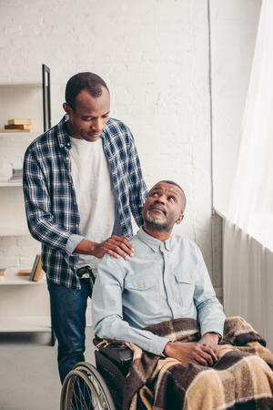 adult african american son looking at disabled senior father in wheelchairの写真素材