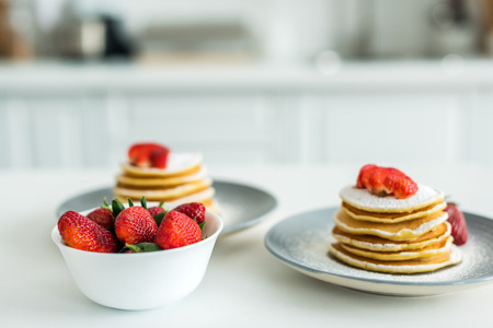 pancakes with ripe strawberries on table at kitchenの写真素材