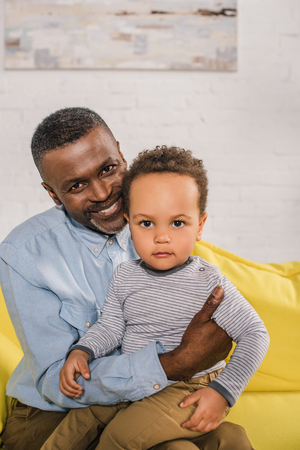 happy african american grandfather and adorable little grandson looking at cameraの写真素材