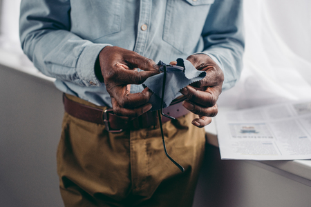 cropped shot of senior african american man cleaning eyeglasses with clothの写真素材