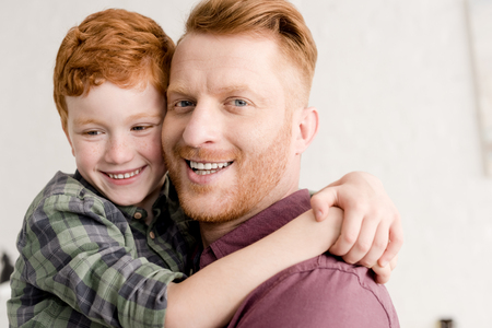 close-up portrait of happy redhead father and son hugging at homeの写真素材