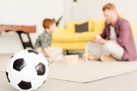 close-up view of soccer ball and father with son playing behindの写真素材