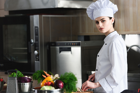 Professional female chef cutting ingredients on restaurant kitchenの写真素材