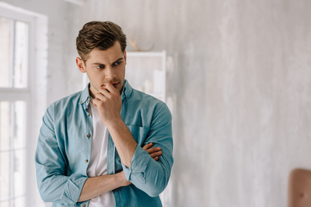 Thoughtful young man wearing lounge wear clothes at home